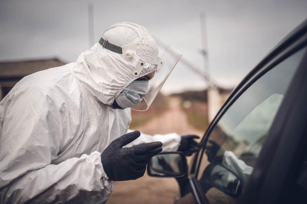 Health care worker in PPE outside of a car