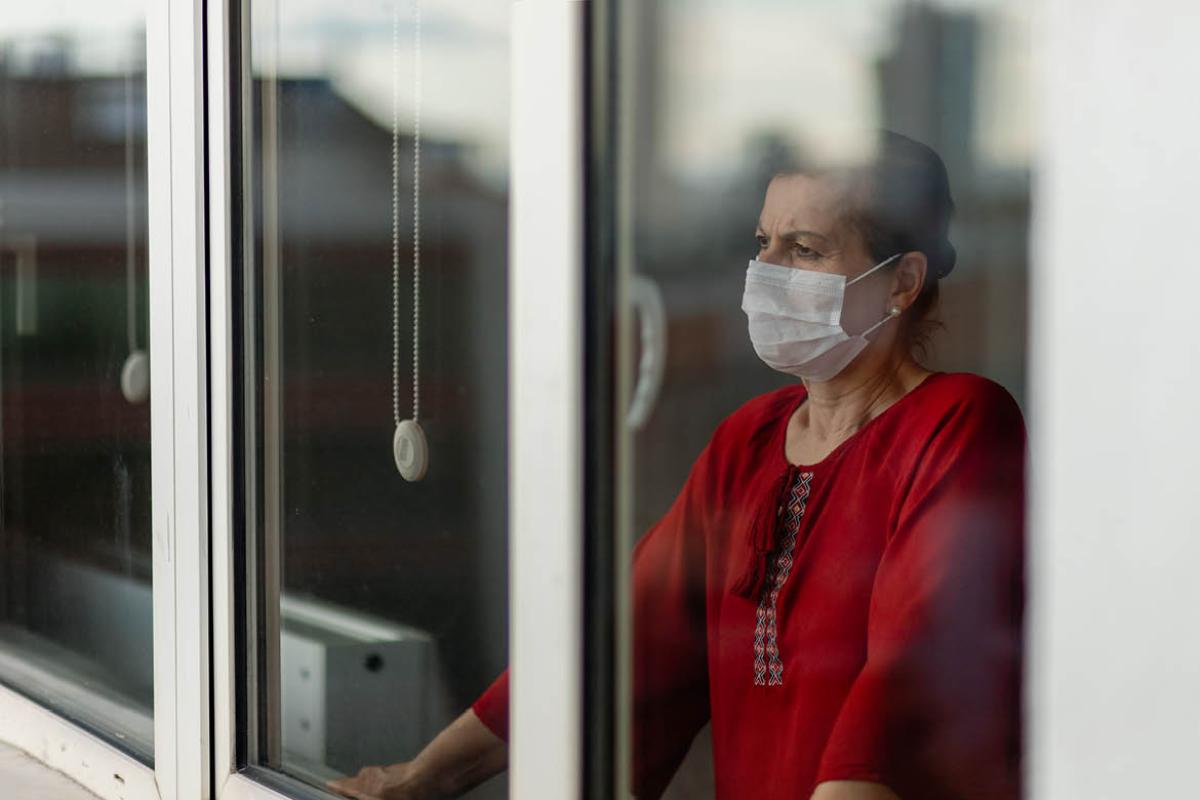 Person wearing a face mask and looking out the window