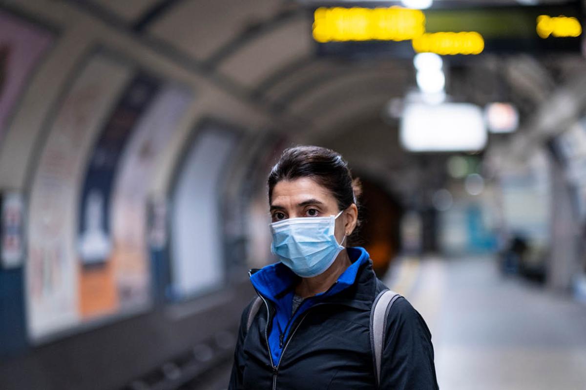 Person wearing facemask in an empty underground train station