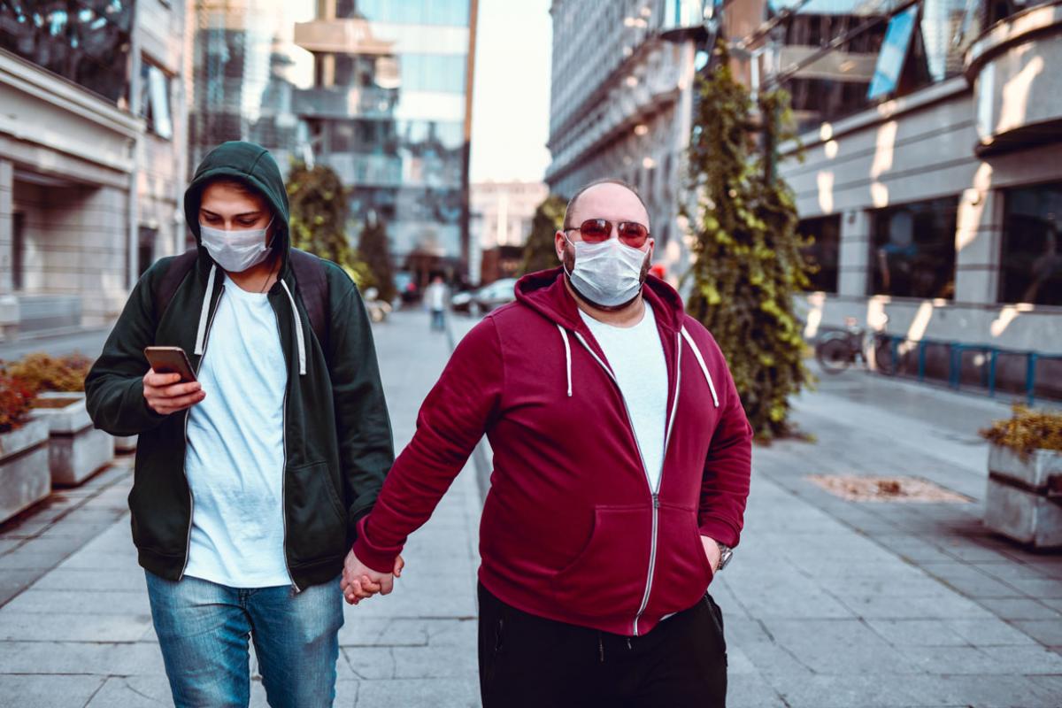 Two people in facemasks holding hands
