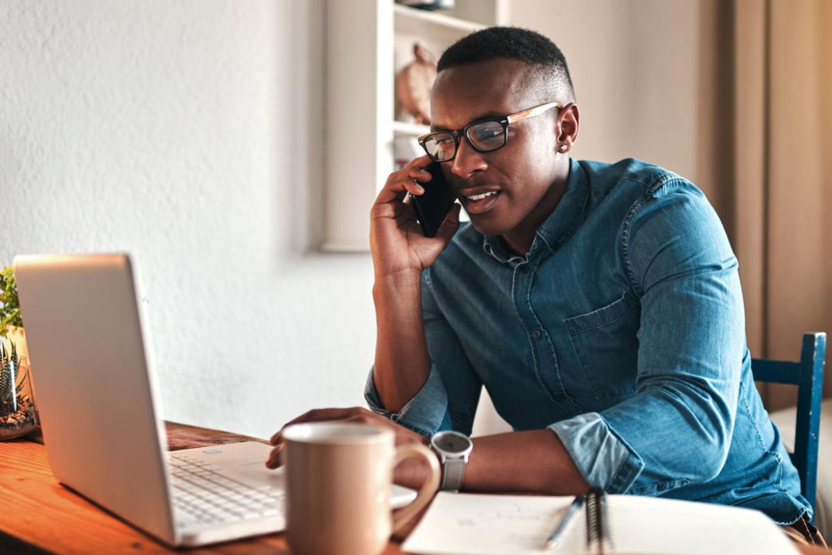 Man using laptop while talking on smartphone