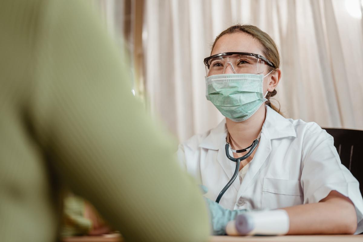 Doctor in mask talking to patient in foreground