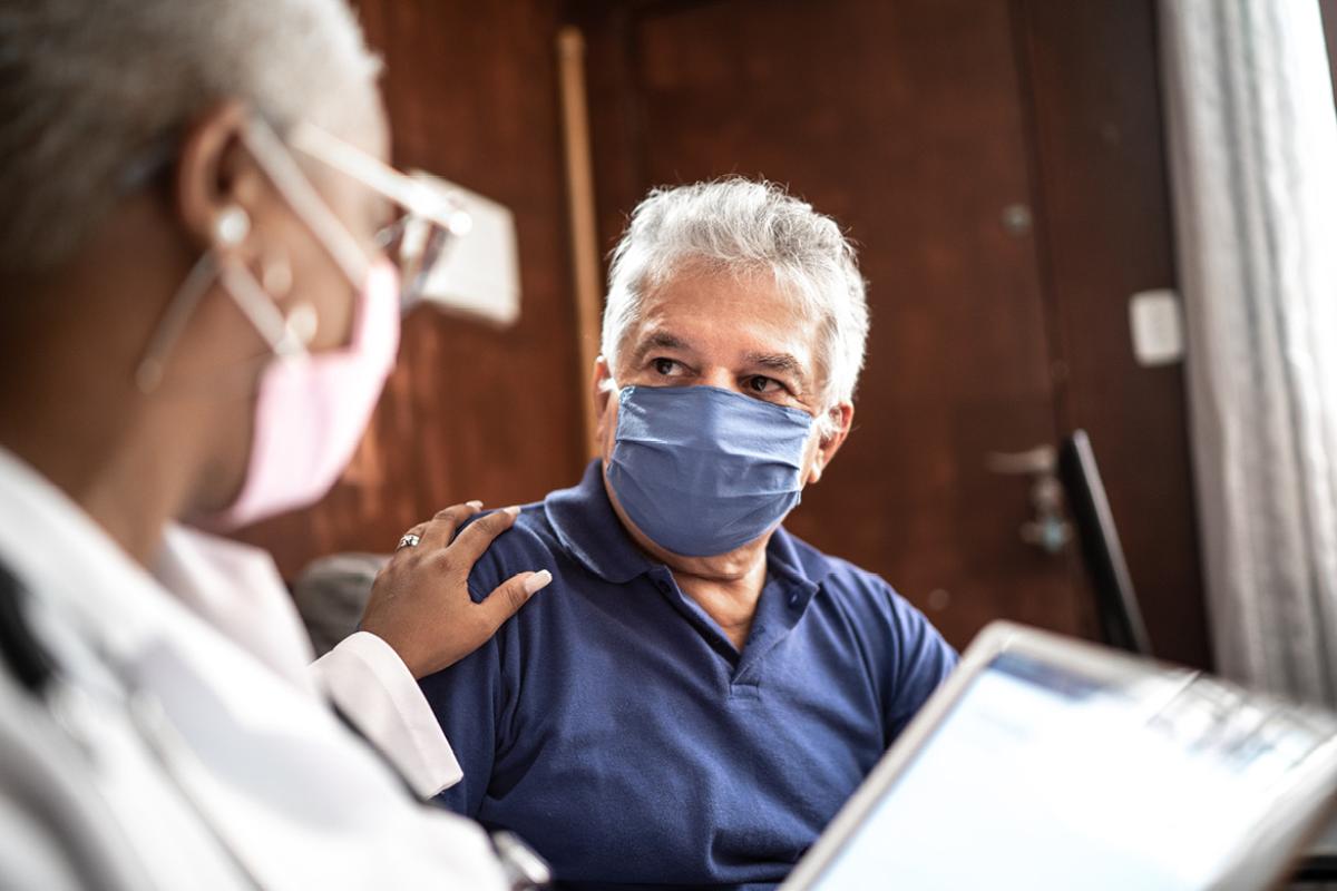 Doctor speaking to a Latinx patient, both wearing masks.