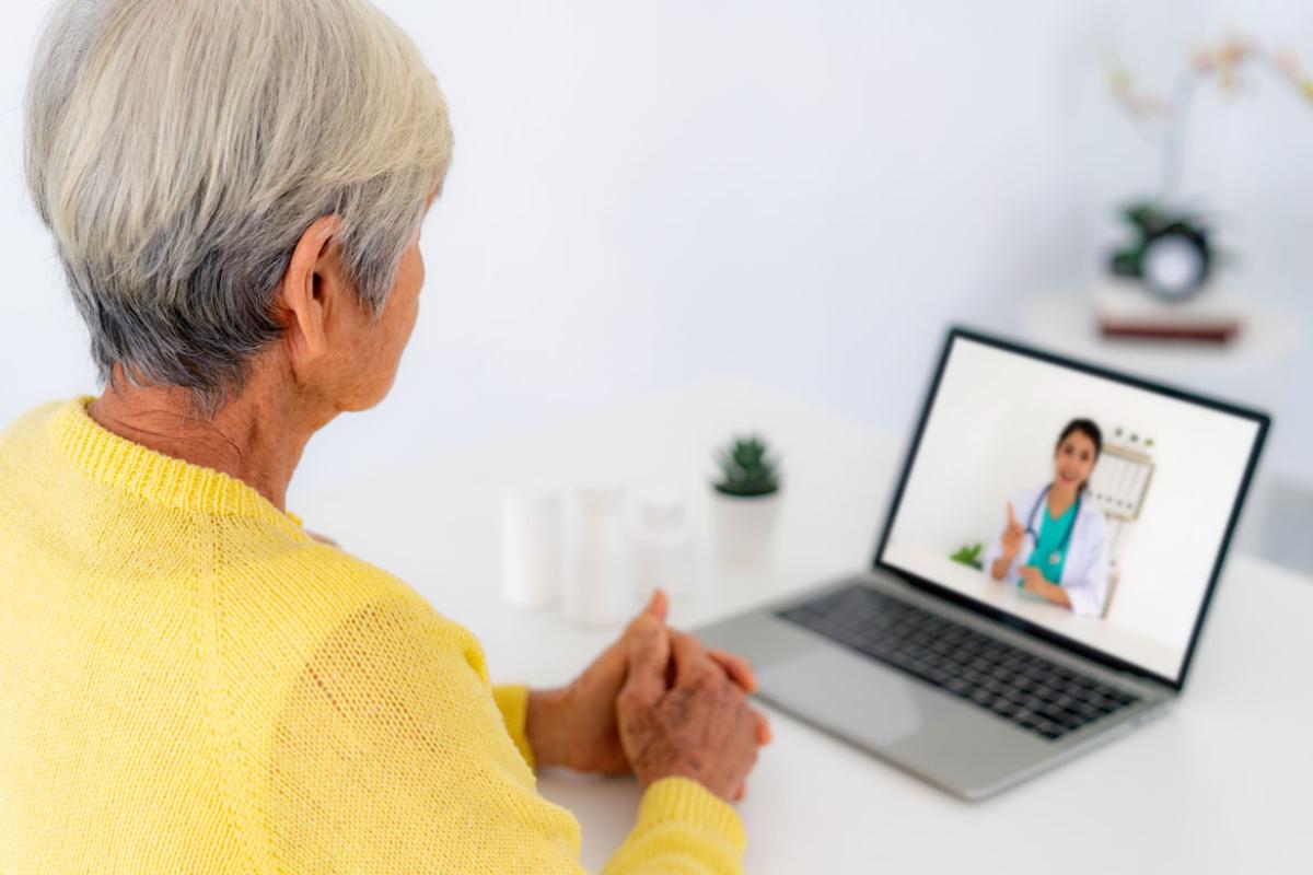A woman talking to a doctor on her laptop computer.