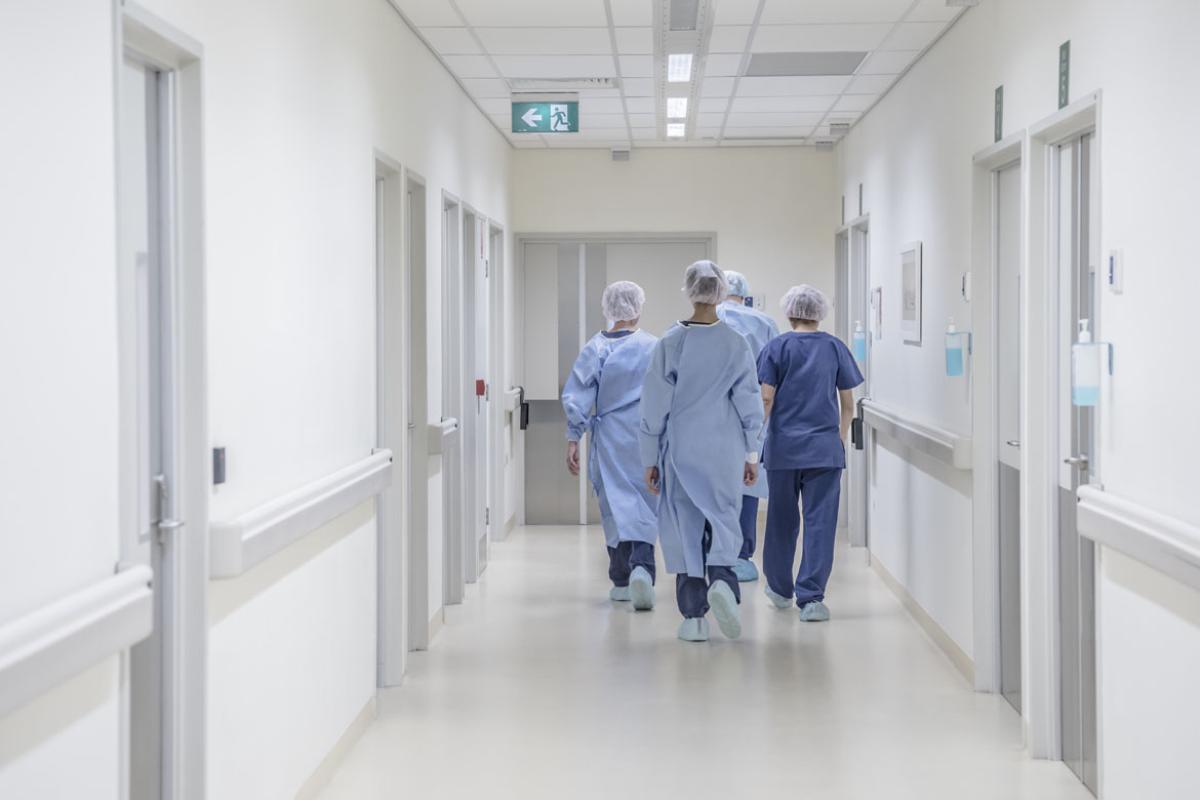 A group of doctors walking down a hospital corridor seen from behind.