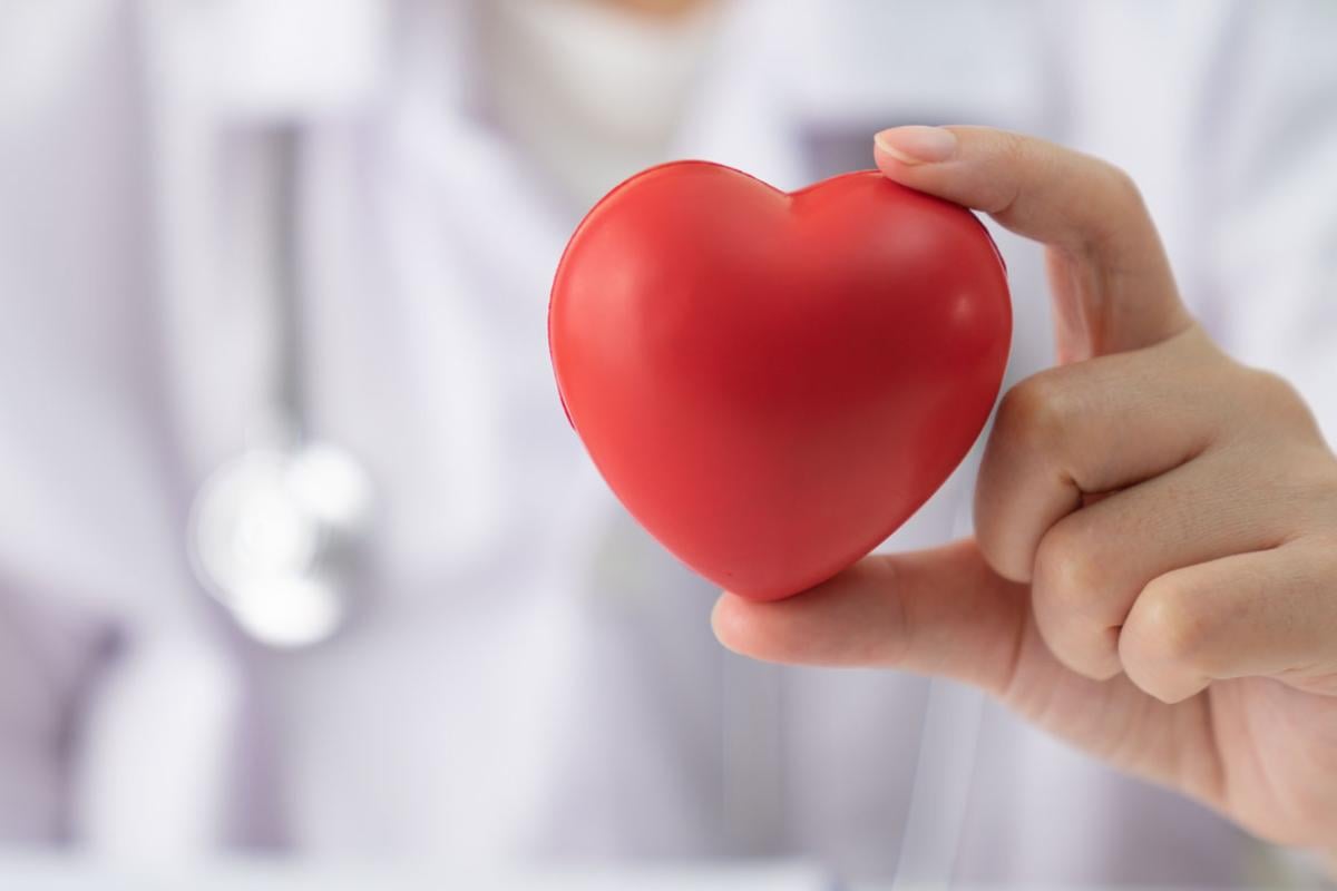 Close-up of a hand holding a red stress ball shaped like a heart.