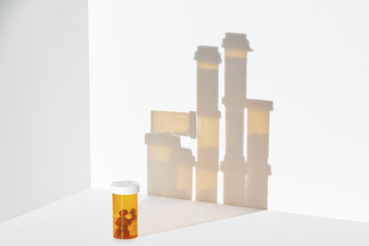 Bottle of pills in foregroud with background of more bottles in shadow