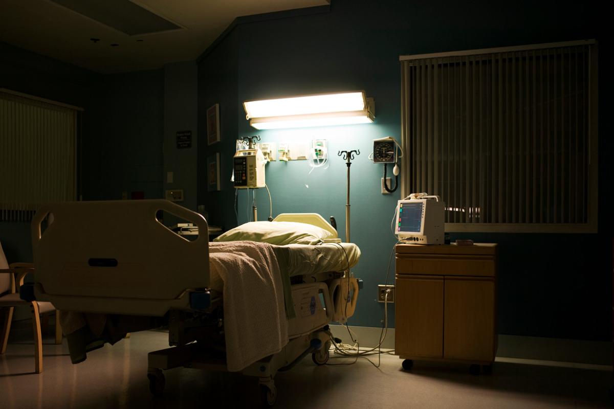 Empty hospital bed at night lit from above.