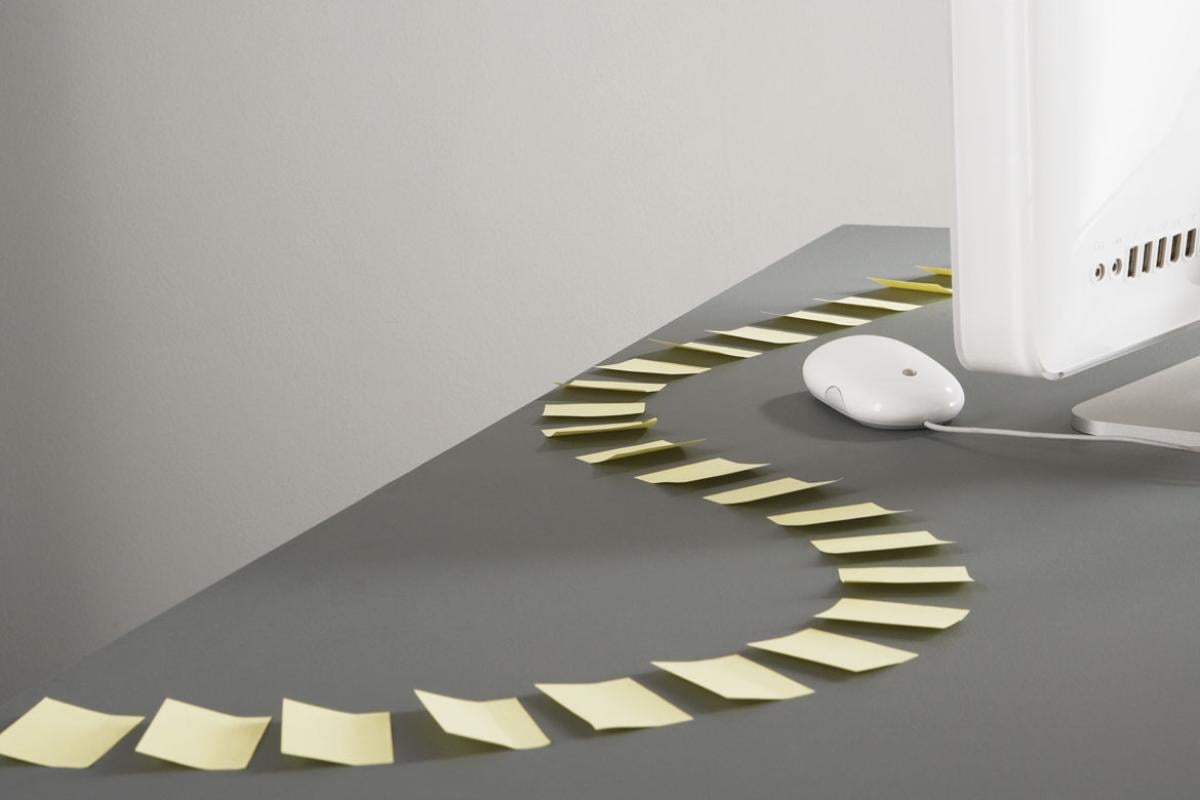 Trail of sticky-notes in an s-curve pattern leading to a computer.