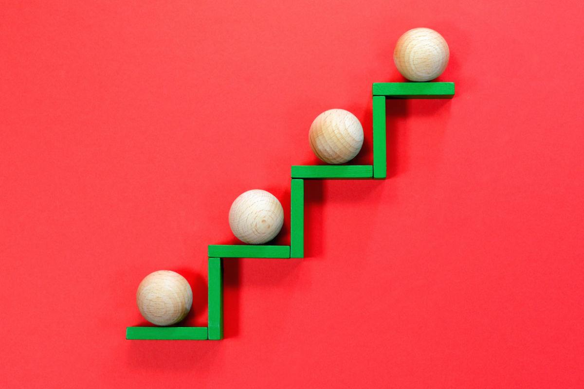 Four wooden balls on a green stair-step pattern of wooden planks against a red background