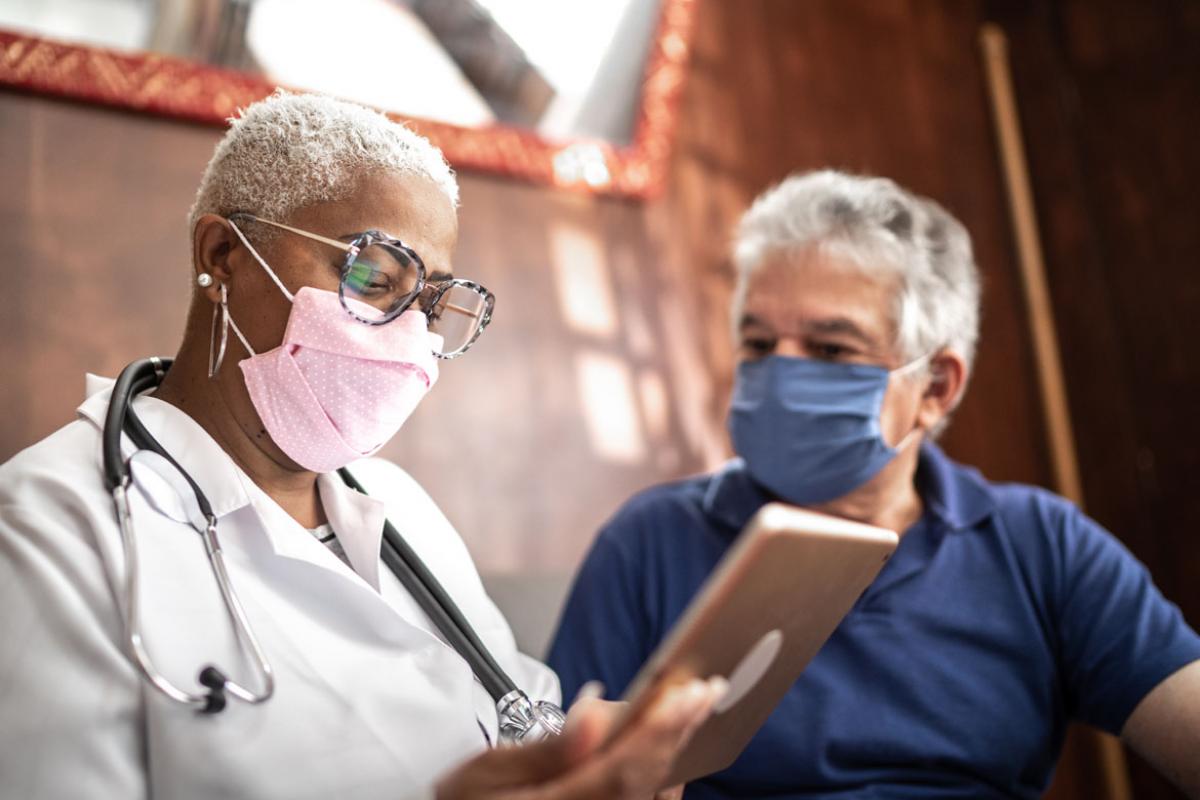 Patient and physician wearing face masks and looking at a tablet