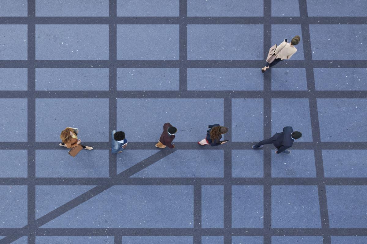Seen from above, a single-file line of five people walking along a grid of dark grey lines against a lighter grey, with one lone woman standing apart from the group.
