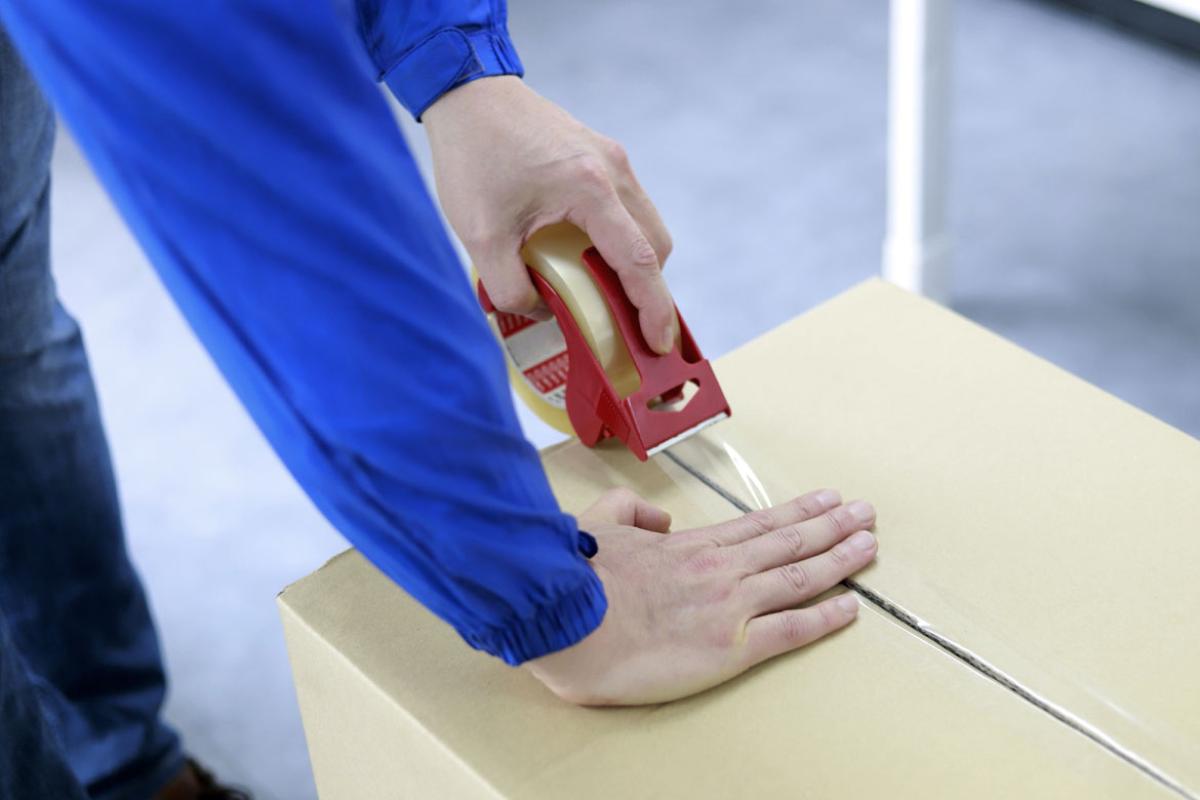 Close-up of a pair of hands taping a box shut.