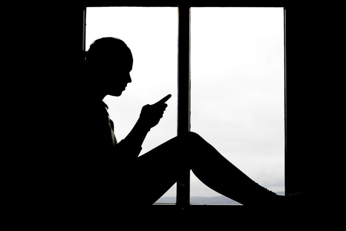 Silhouette of a person looking at a smartphone
