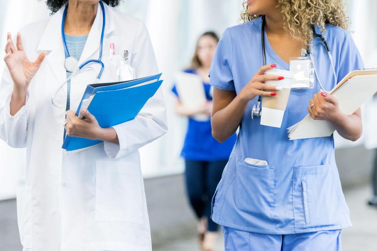 Two health care workers walking and talking, shown from the neck to the waist
