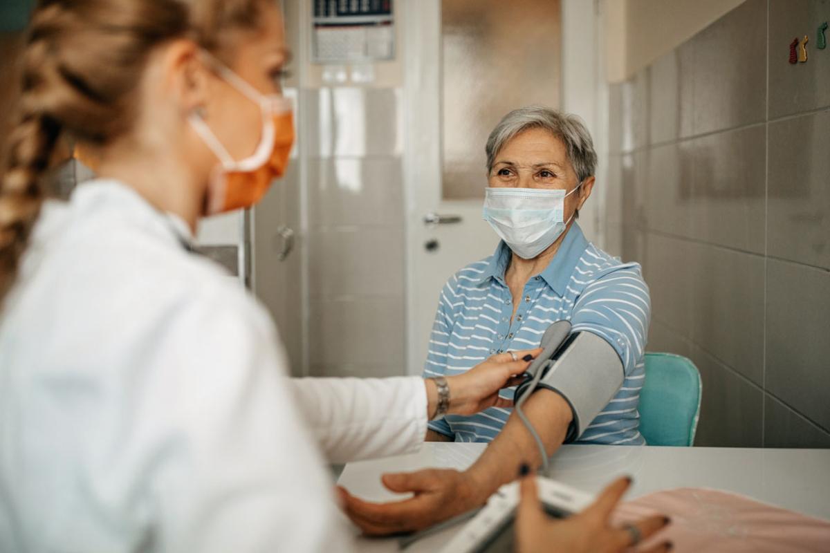 Woman having blood pressure monitored by physician
