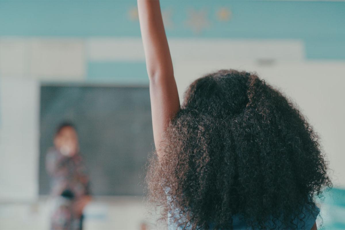 Young person raising their hand in a classroom