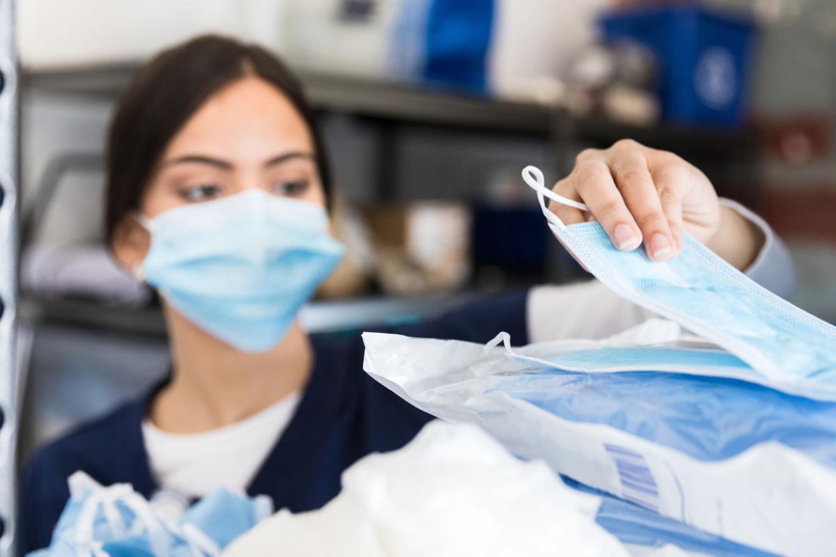 Health care worker or nurse wearing mask, and checking medical supplies