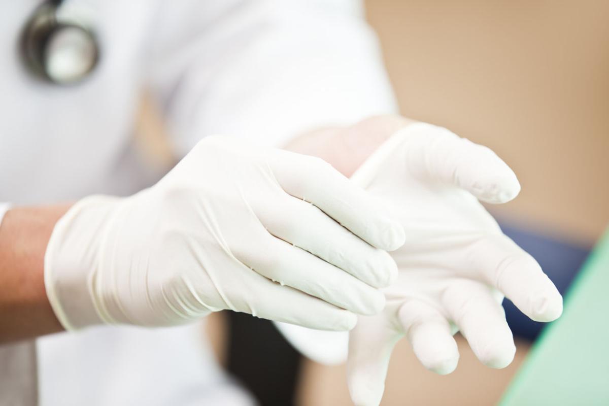 Health care professional putting on examination gloves