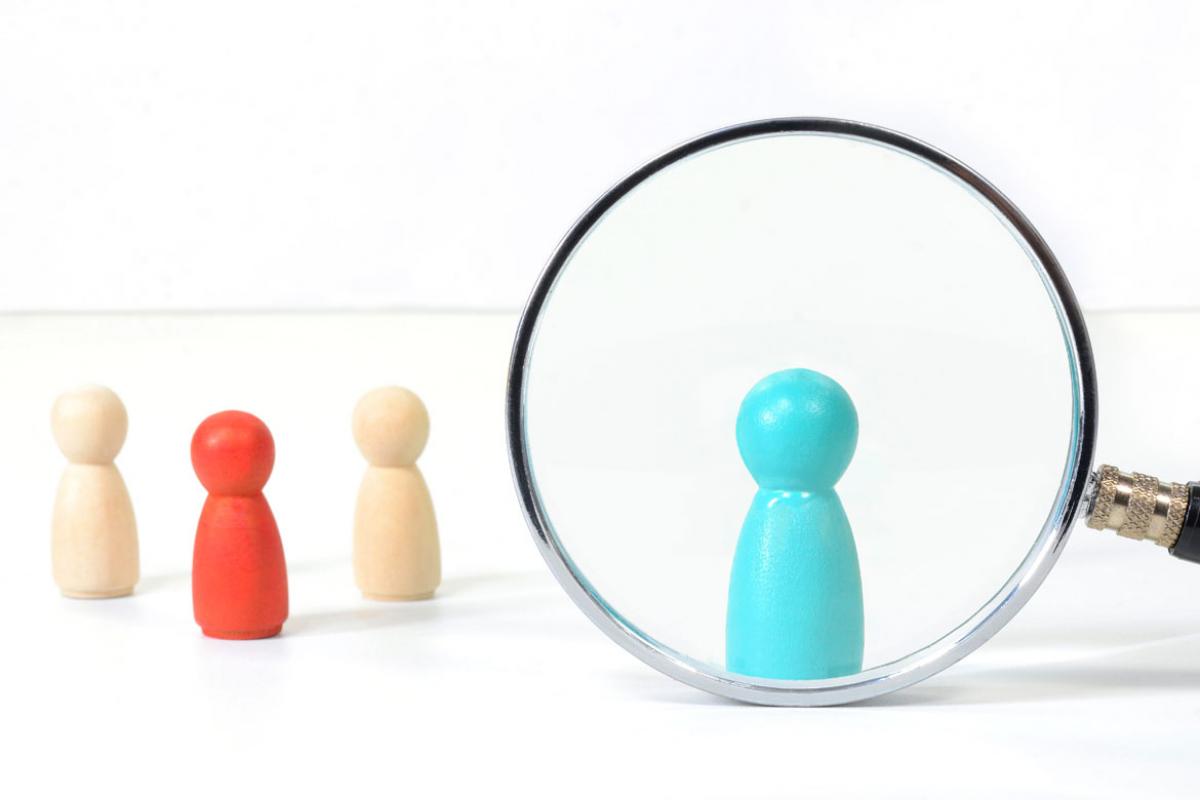 Different colors of figurines with one under a magnifying glass