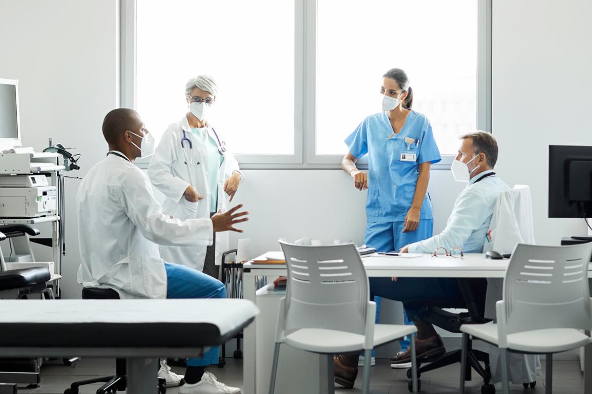 Four health care professionals having a meeting in a brightly lit hospital office.