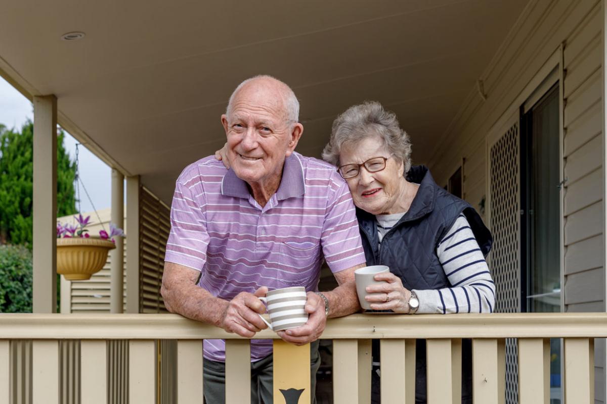 Senior couple on a porch, drinking coffee.
