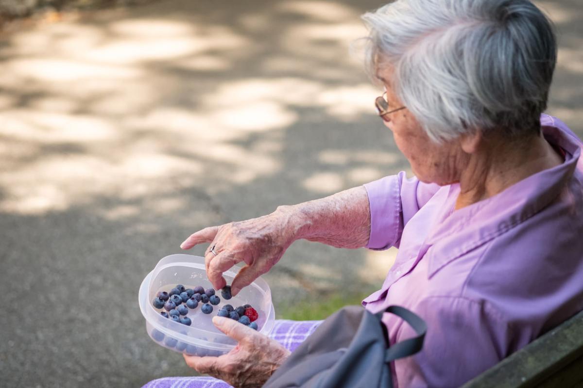 Elderly woman eating fruit outside