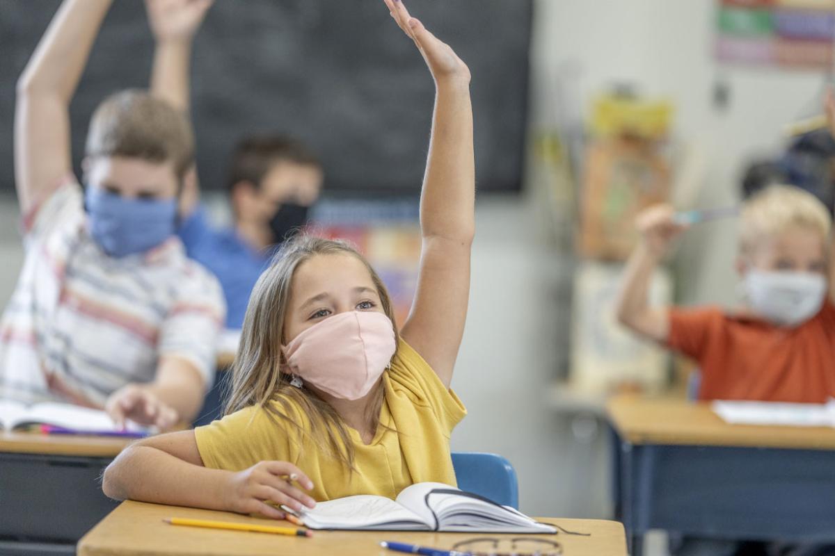 Children in a classroom raising their hands