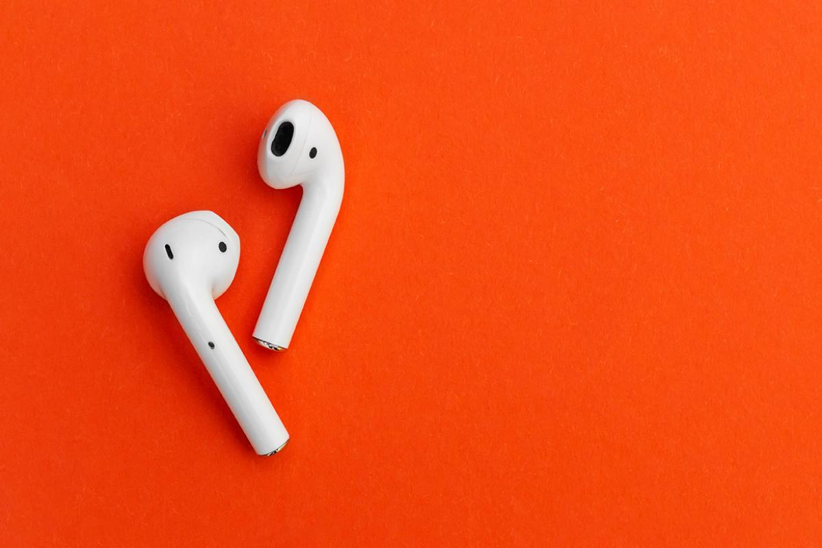 White earbuds sitting on an orange background.