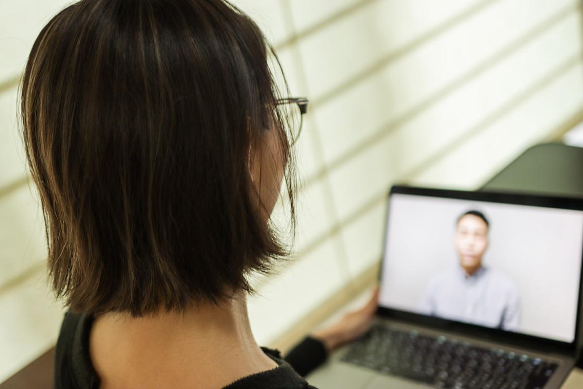Back head of young woman on a laptop participating in a virtual interview