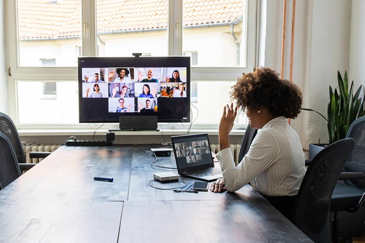 Woman meeting with colleagues over a video conference call using a laptop and big screen monitor