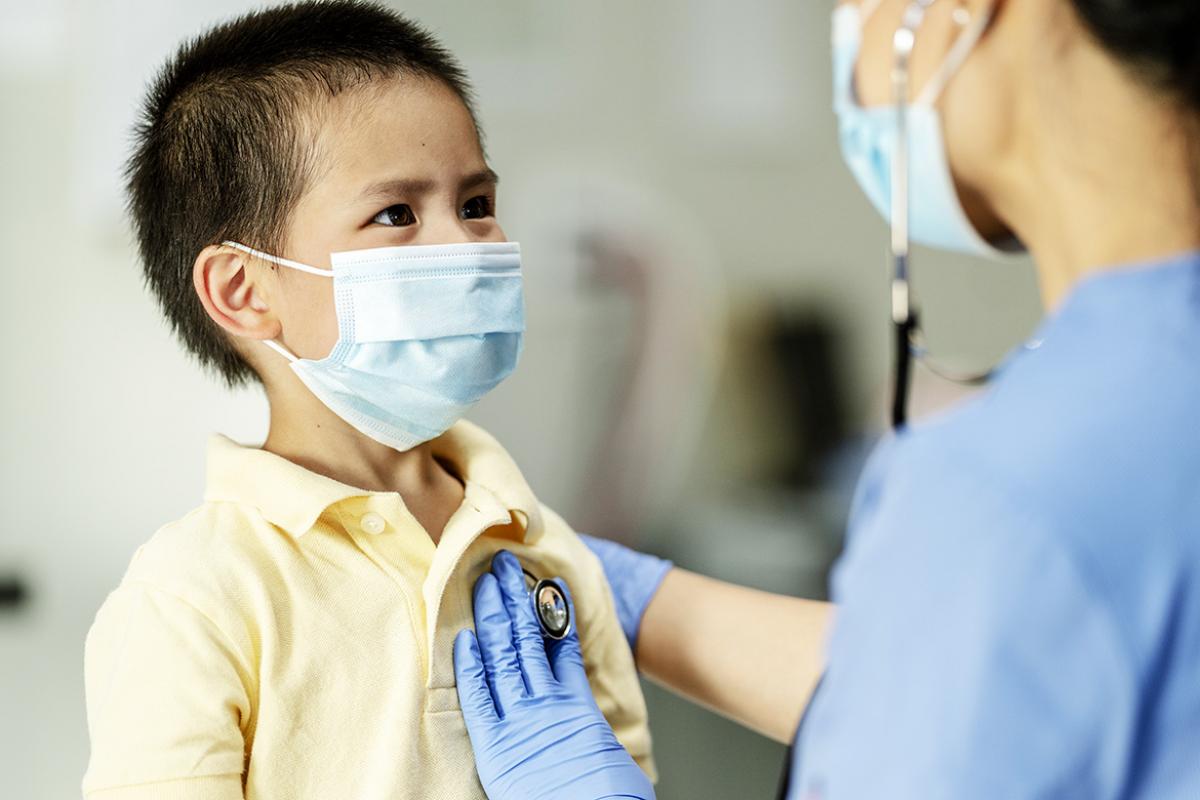 Young boy being checked by a physician, both wearing masks