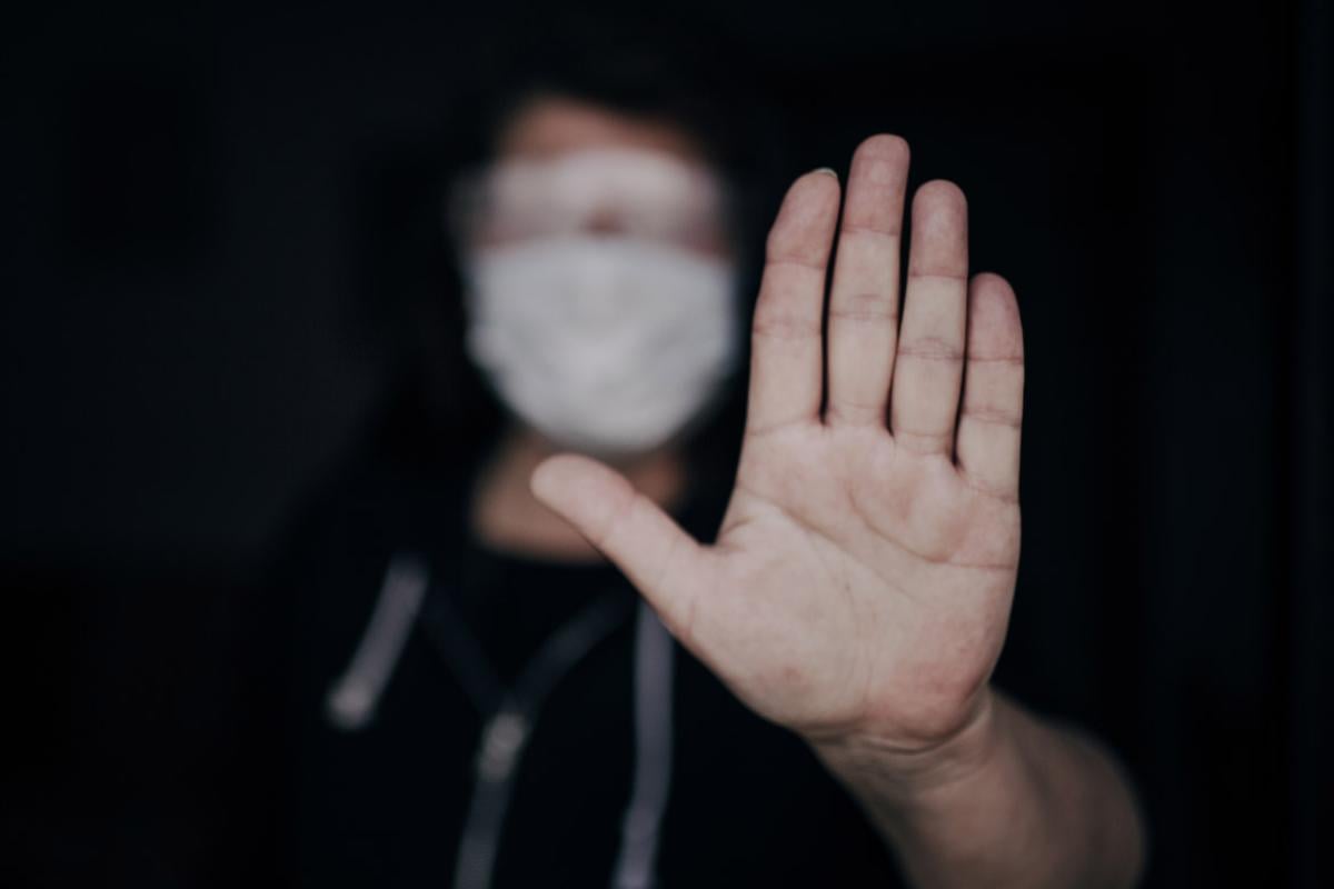 Health care worker wearing a mask with a hand palm up in a gesture to stop