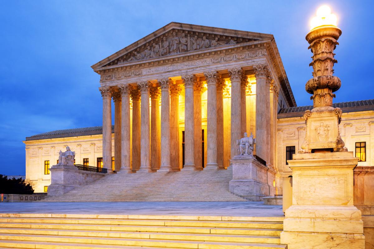 U.S. Supreme Court building exterior and steps with lights turned on in the portico