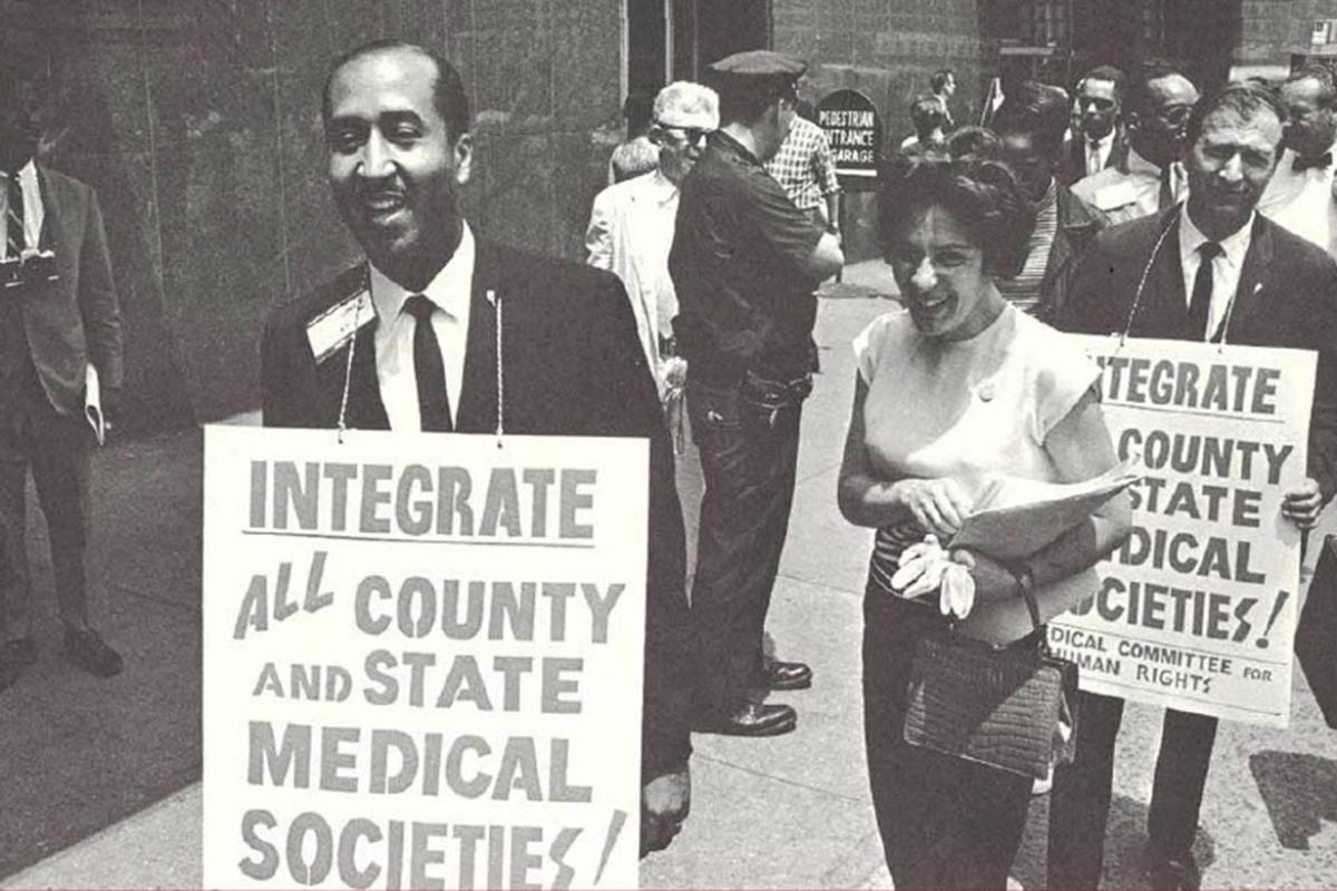 Black and white historical photo of people marching to integrate county and state medical societies