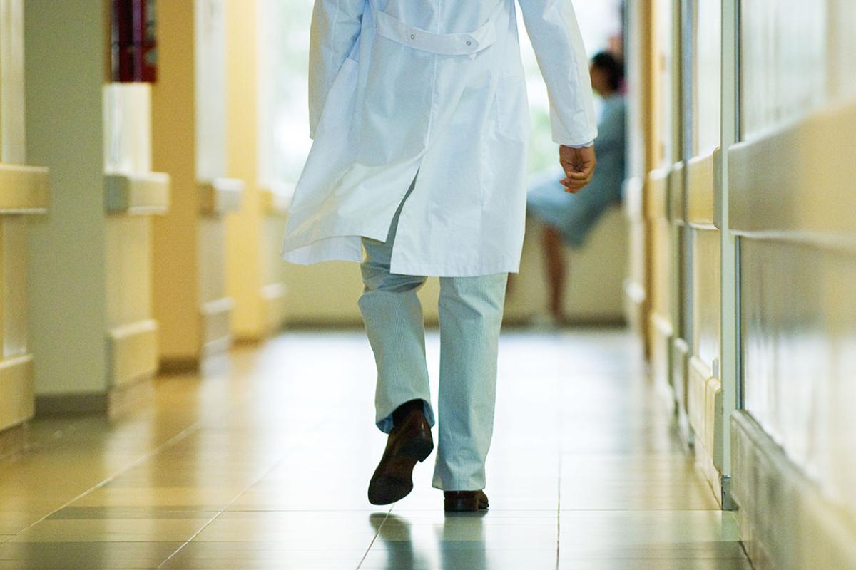 Back shot of a physician in a hurry walking down a hospital hallway