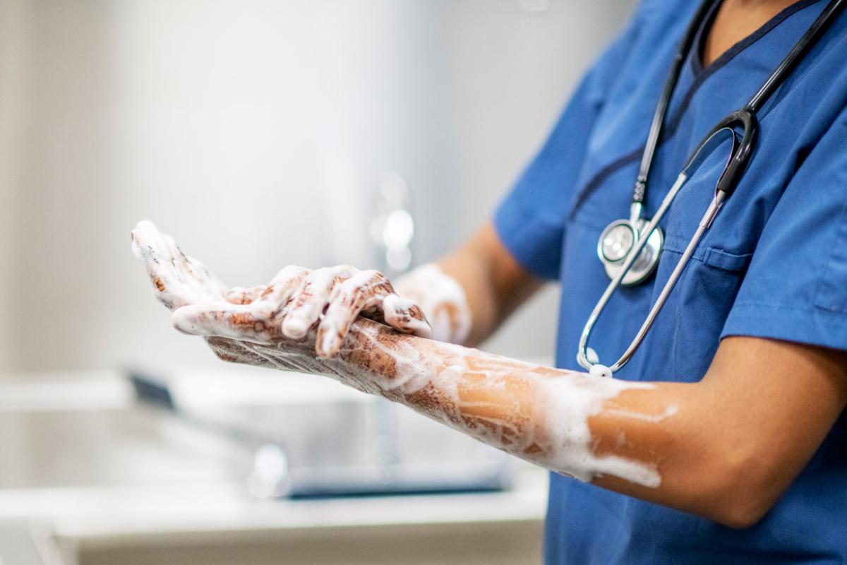 Physician wearing scrubs and a stethoscope and washing hands