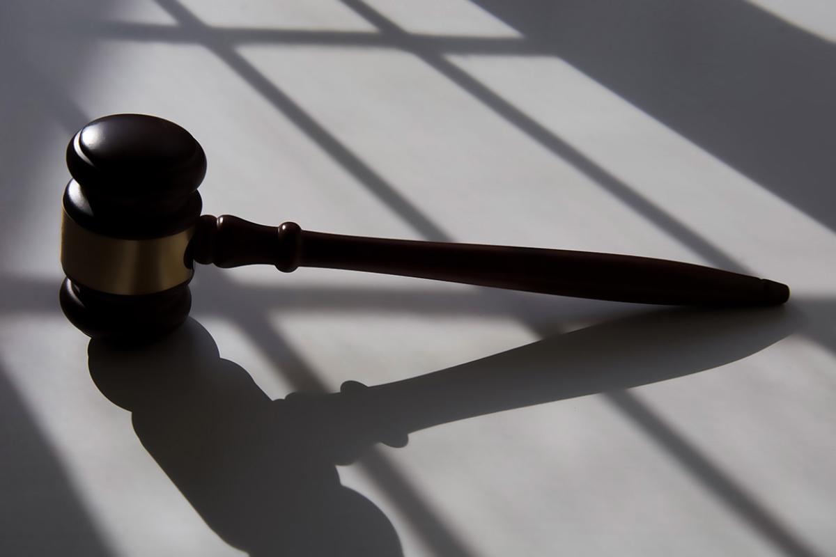A gavel on a blank surface and the shadow of the gavel and some bars