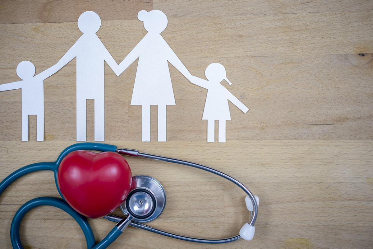 Paper cutouts of a family alongside a stethoscope entwined with a plastic heart