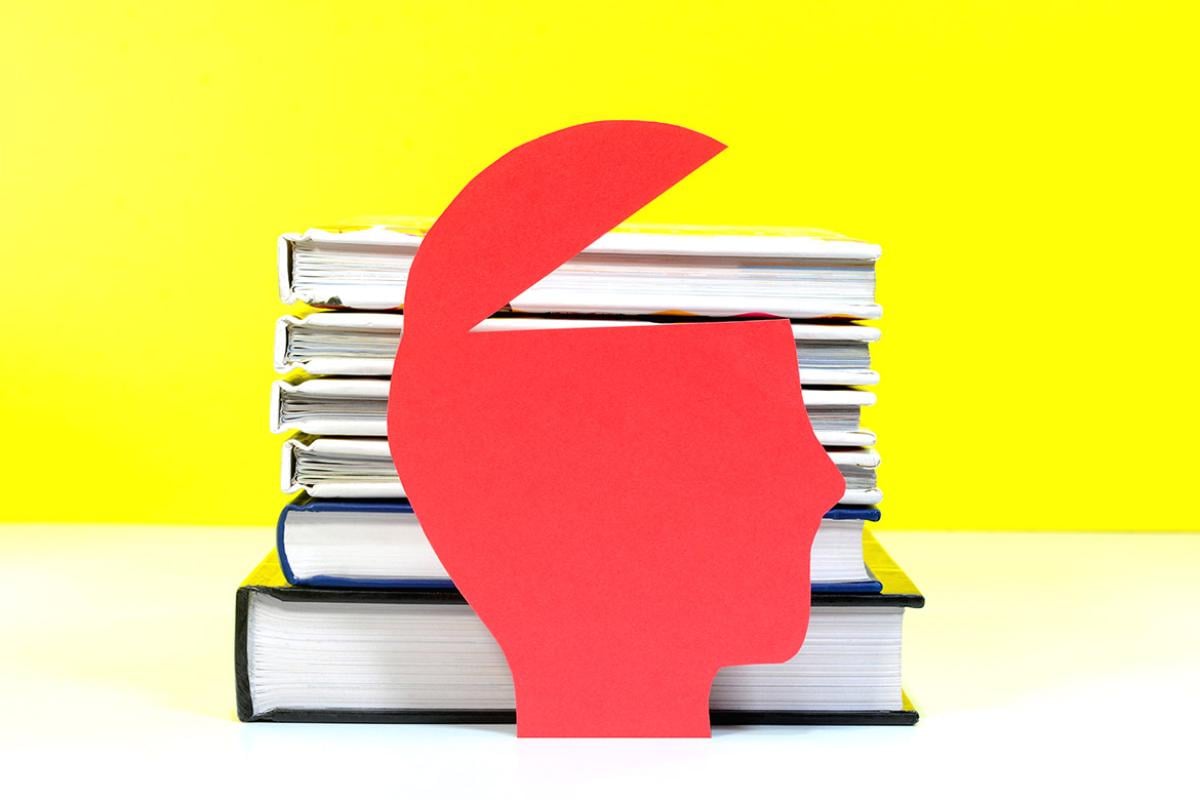 A paper cut out of a human head with a stack of books behind it