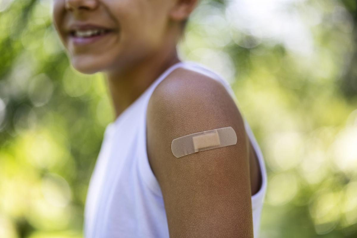 Tight shot of young boy's arm with an adhesive bandage after receiving a vaccination