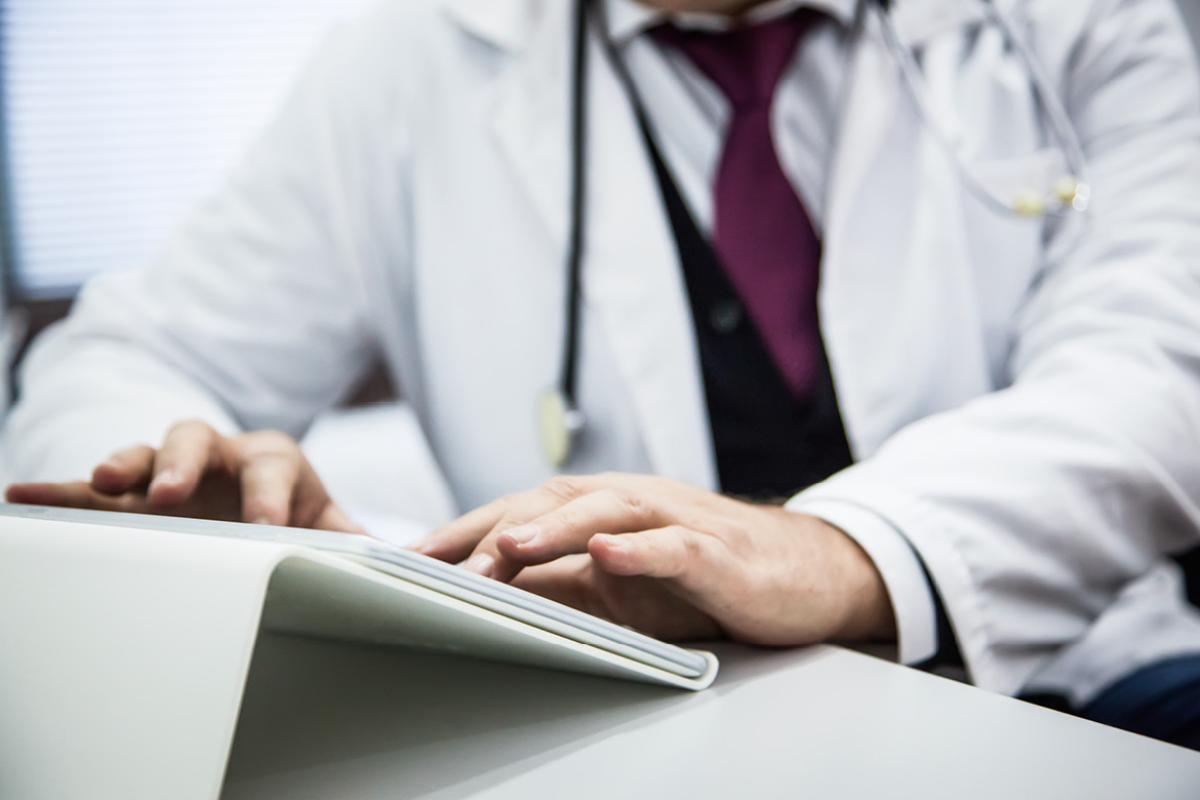 Close up of physician typing on tablet positioned on a stand or holder