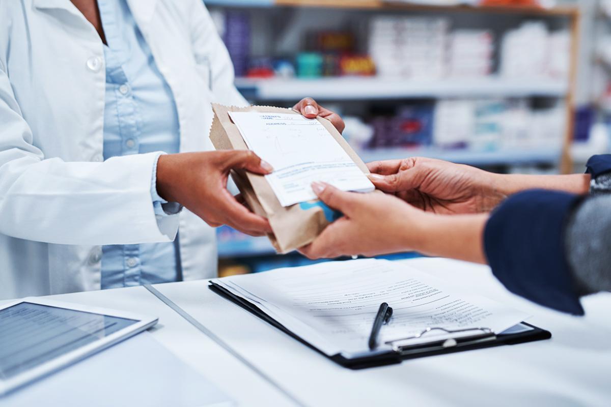 Tight shot of patient receiving a bag with a prescription from pharmacist