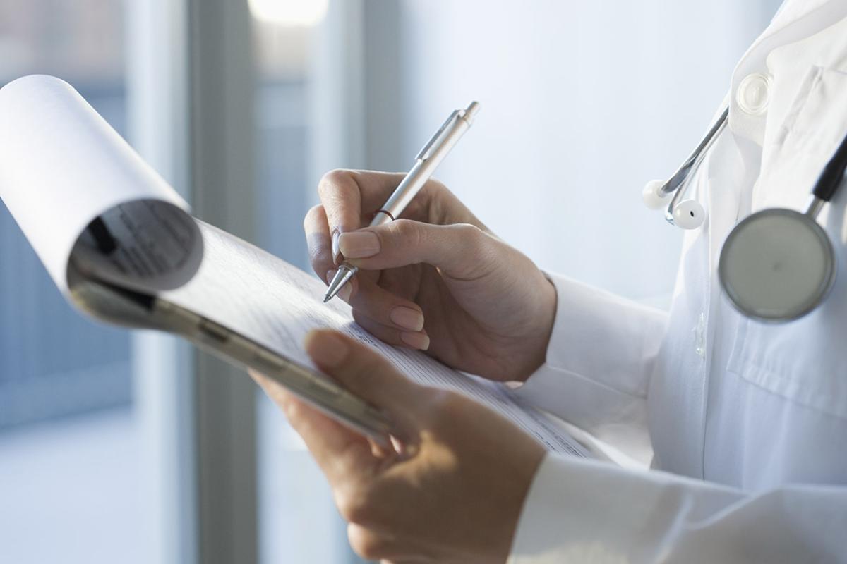 Physician writing notes on a clipboard