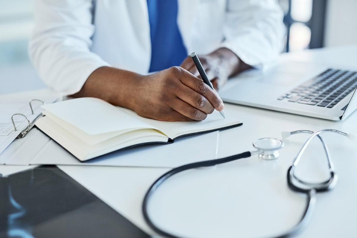 Physician writing notes in notepad