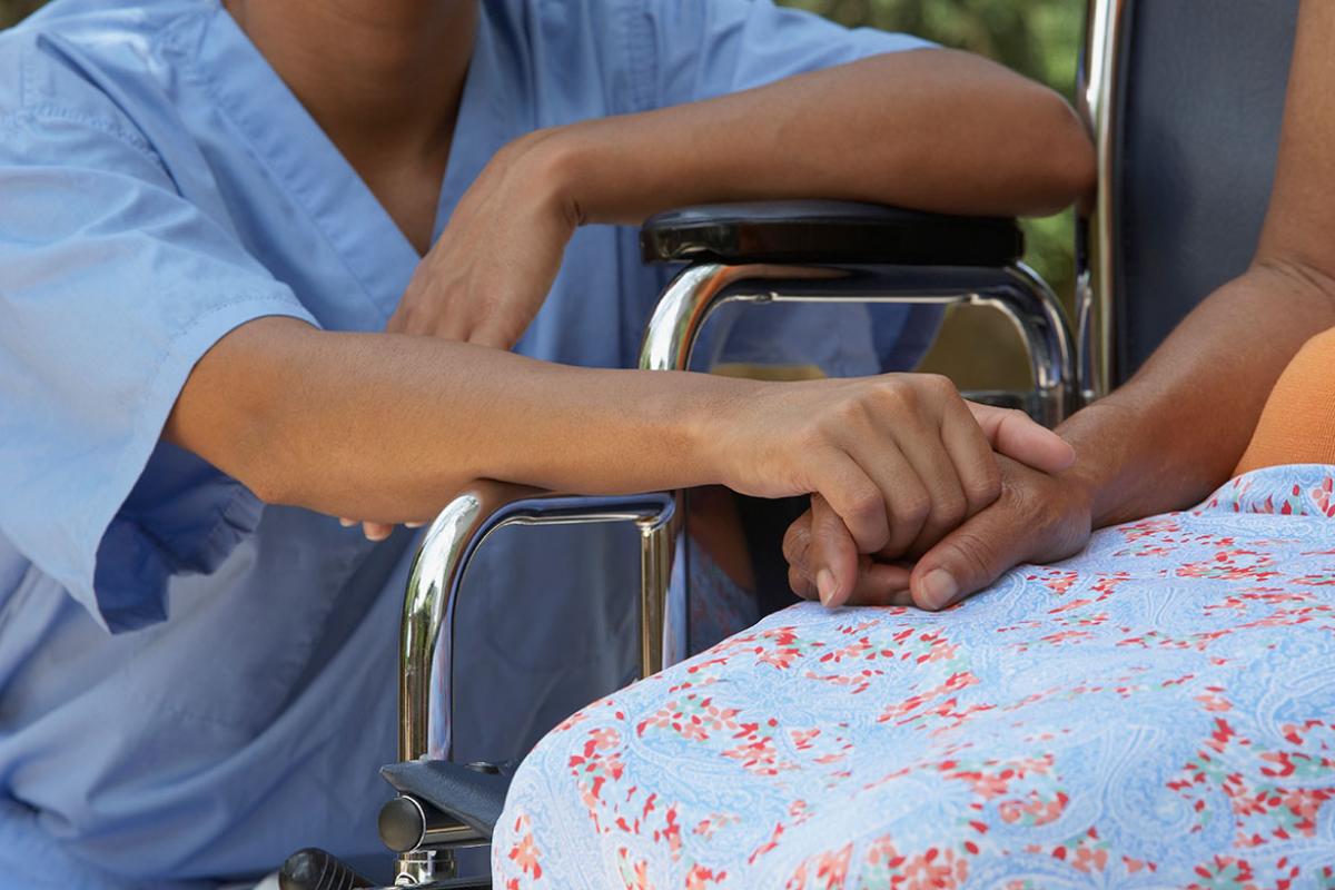 Health care worker holding hand of person in a wheelchair