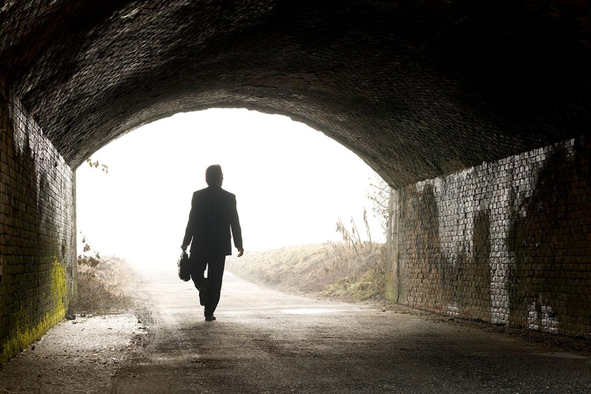 Businessperson walks through brightly lit tunnel 