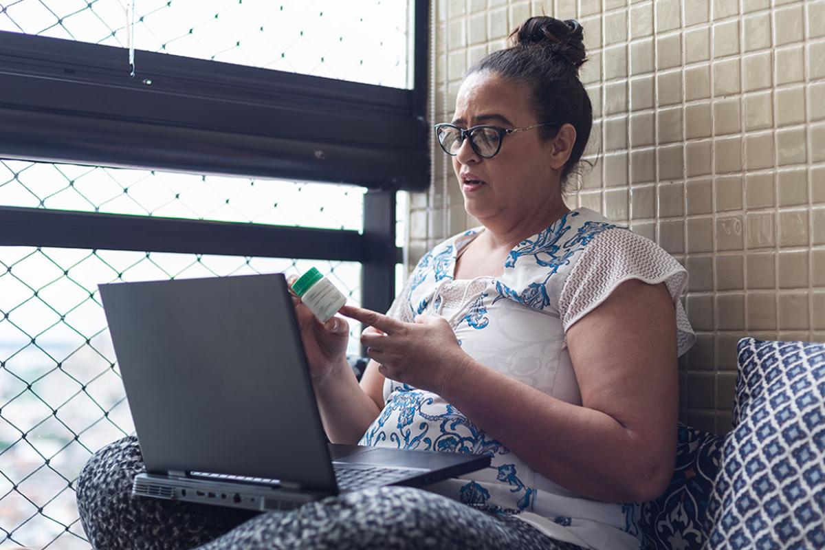 Person looking at prescription bottle in front of laptop