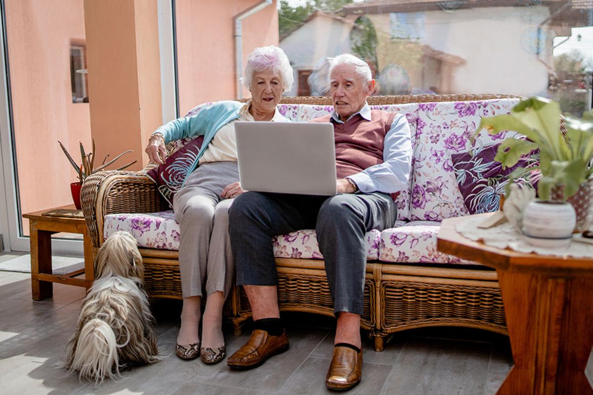 Couple sitting on couch and looking at a laptop