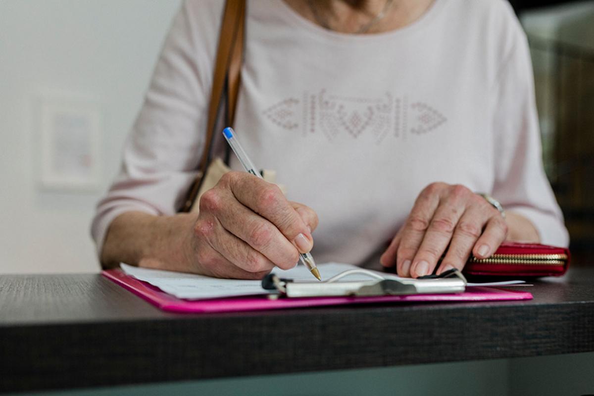 Person filling out a form on a clipboard